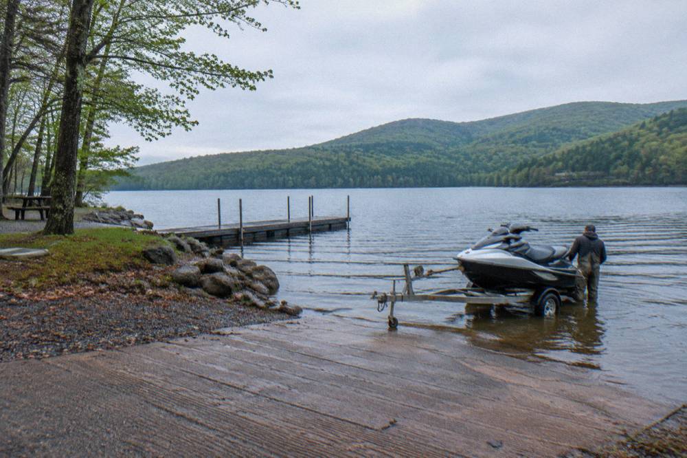 A boat ramp at a lakeside state park with calm water and forested hills in the distance