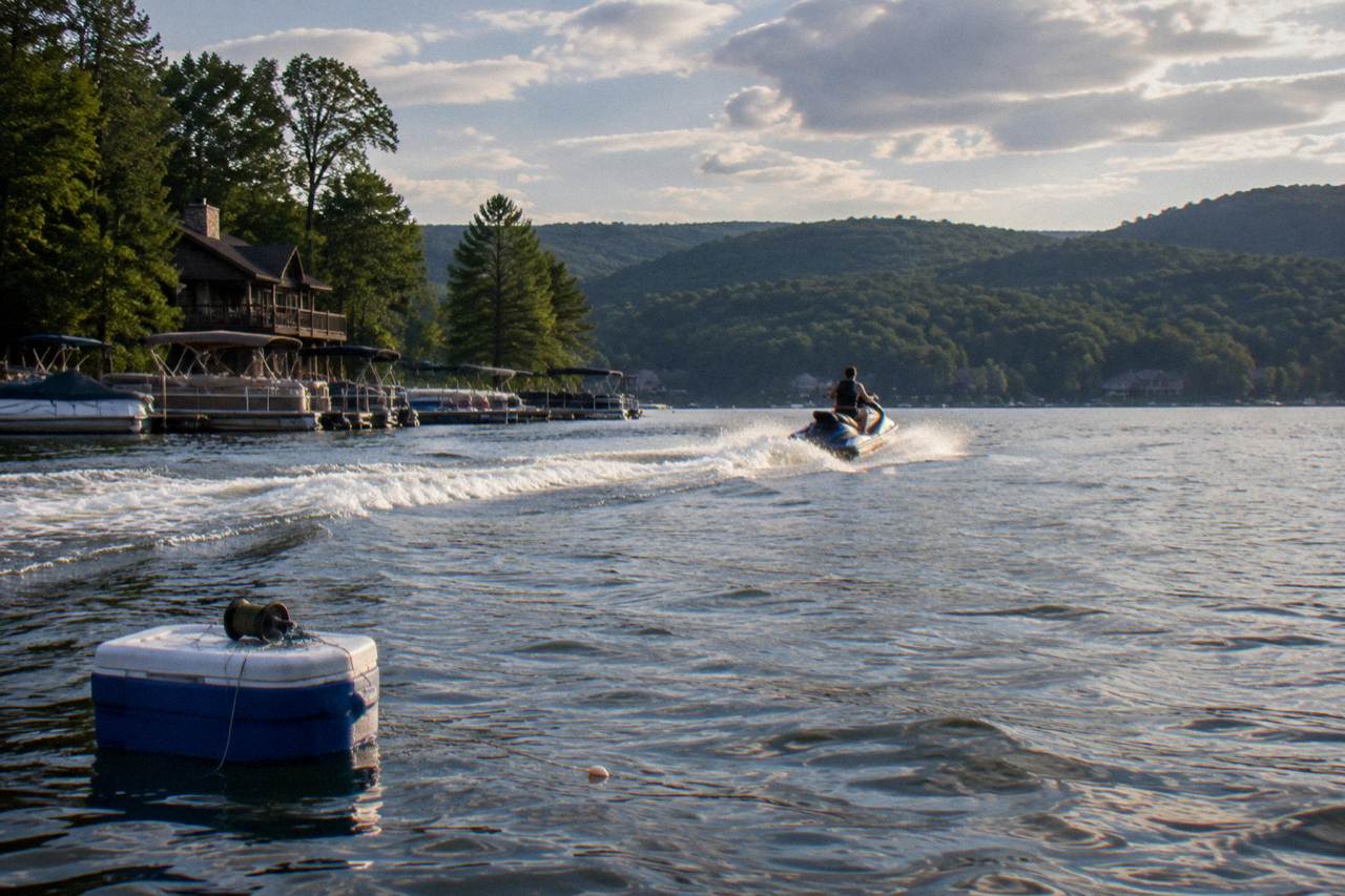 A personal watercraft cutting across open water on a mountain lake surrounded by forested ridges