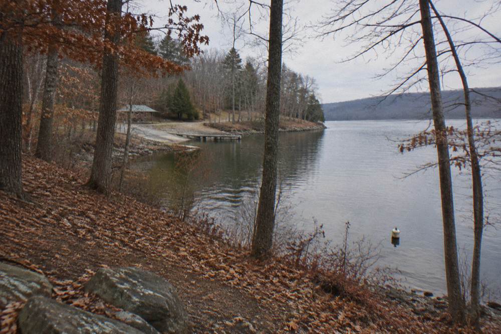 A wooded hillside above Deep Creek Lake with autumn color reflecting in the water
