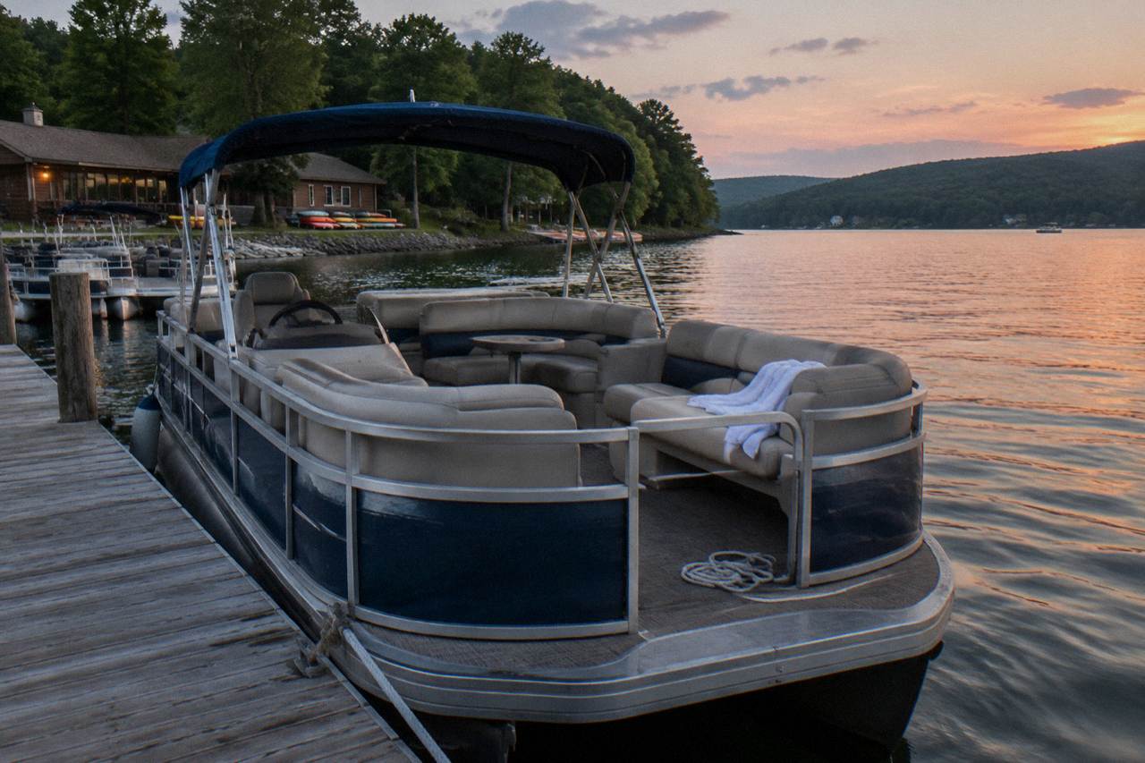 Pontoon boat moored at a wooden dock on a calm mountain lake at golden hour