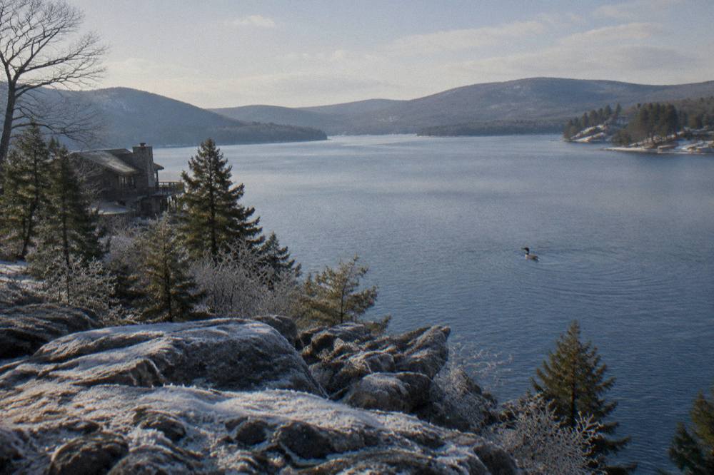 Long view down a mountain lake with wooded points and calm water stretching toward distant hills