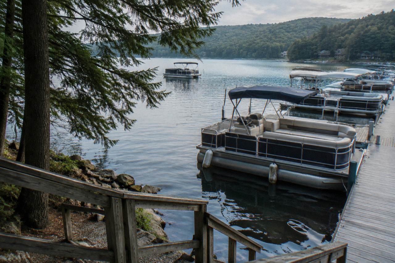 Pontoon boats moored on calm water along a wooded shoreline at Deep Creek Lake