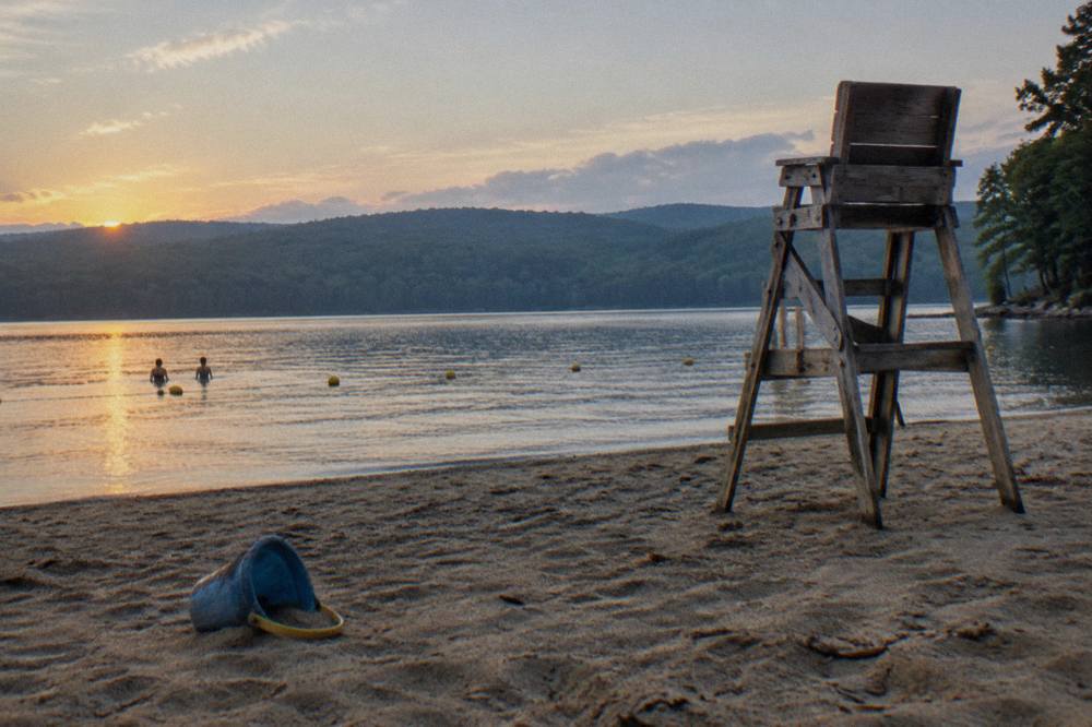 A sandy swim beach at a mountain lake with buoyed swim line and quiet morning water