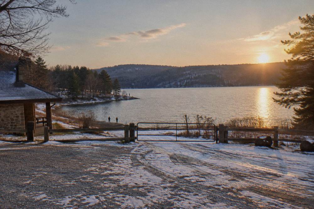 Late afternoon light over a mountain lake with distant forested shoreline and calm open water