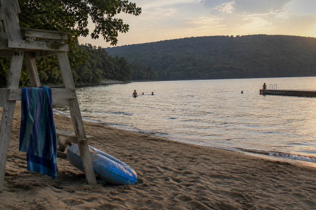 Calm lake water along a wooded shoreline at Deep Creek Lake with distant hills in soft light