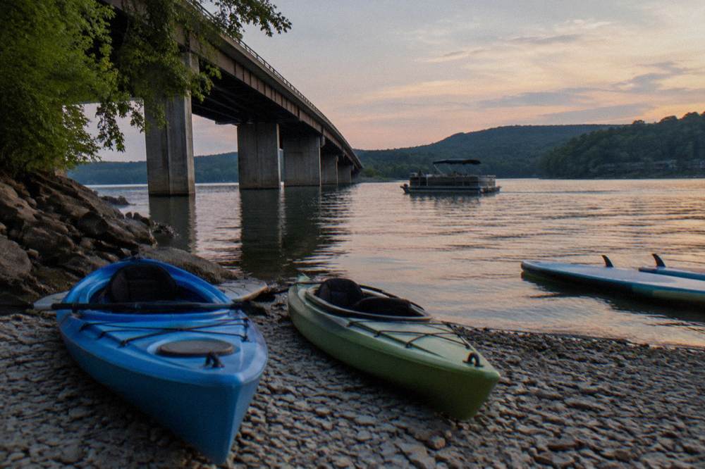 Kayaks resting on a gravel shoreline beside a quiet lake cove