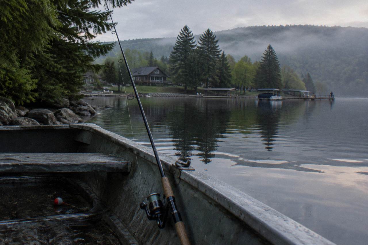 A quiet Deep Creek Lake cove at first light with a fishing rod resting against the gunwale of a small boat