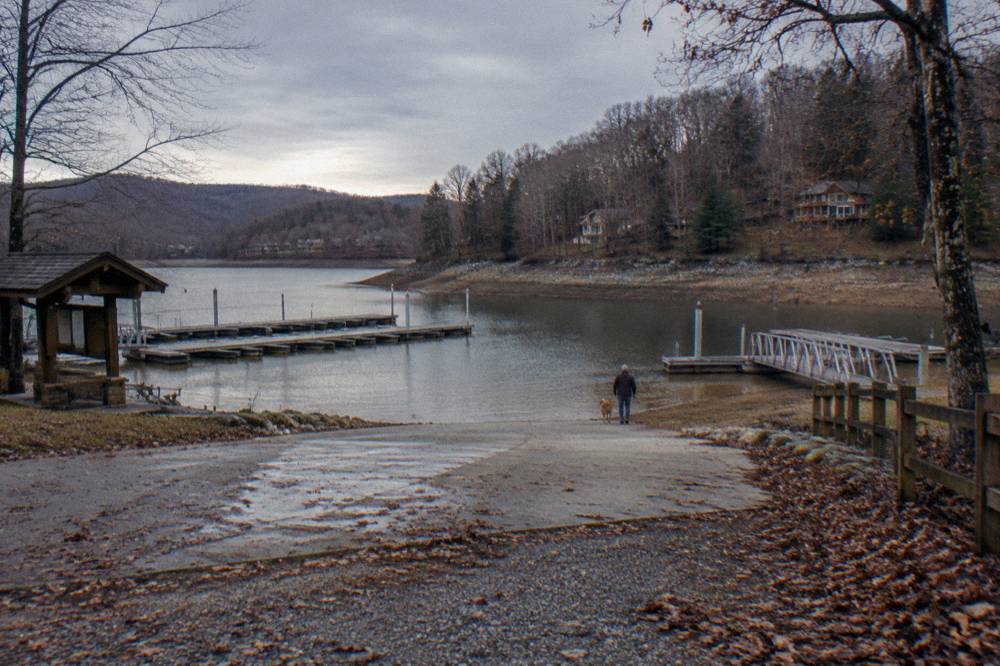 An empty boat ramp at a lake in late autumn with bare trees on the far shore