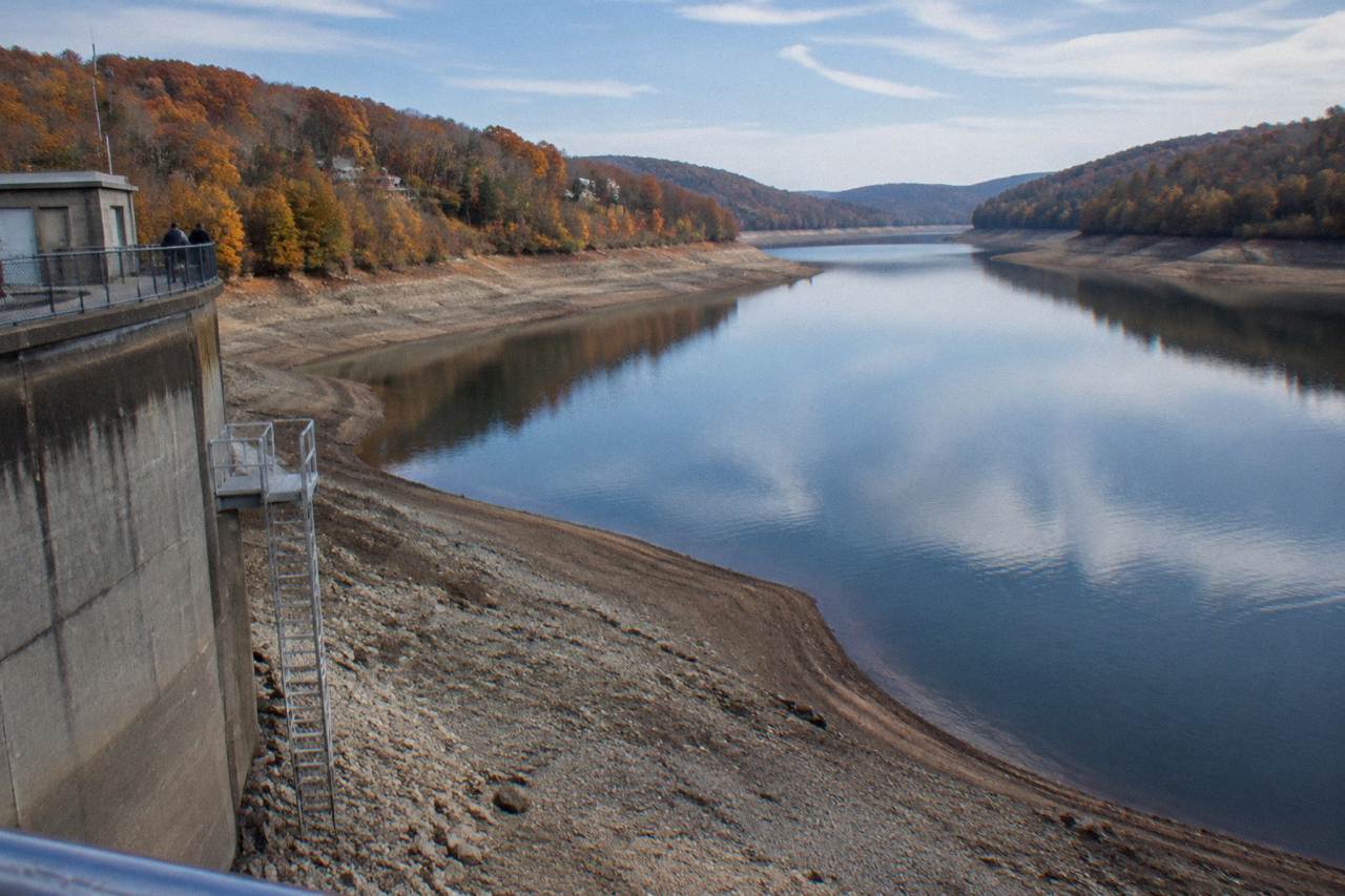 Calm lake water in fall with wooded hills in orange and red color