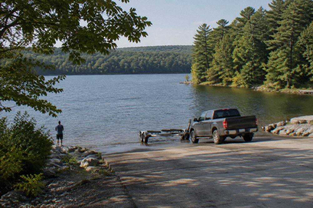 Concrete boat ramp sloping into a quiet lake with forested shoreline