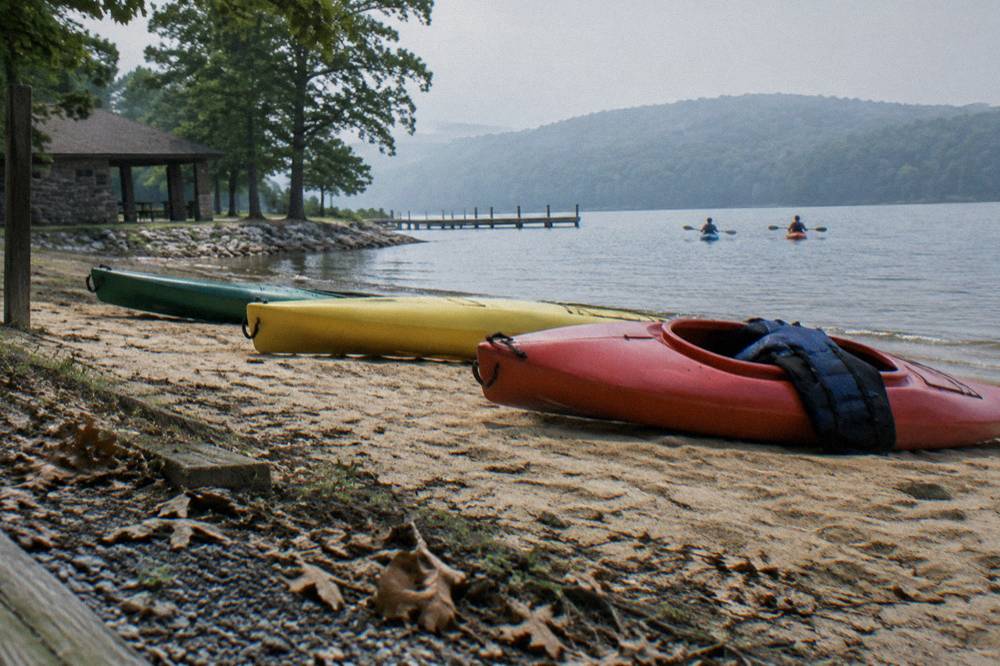 Kayaks resting near a sandy beach launch area at a lake