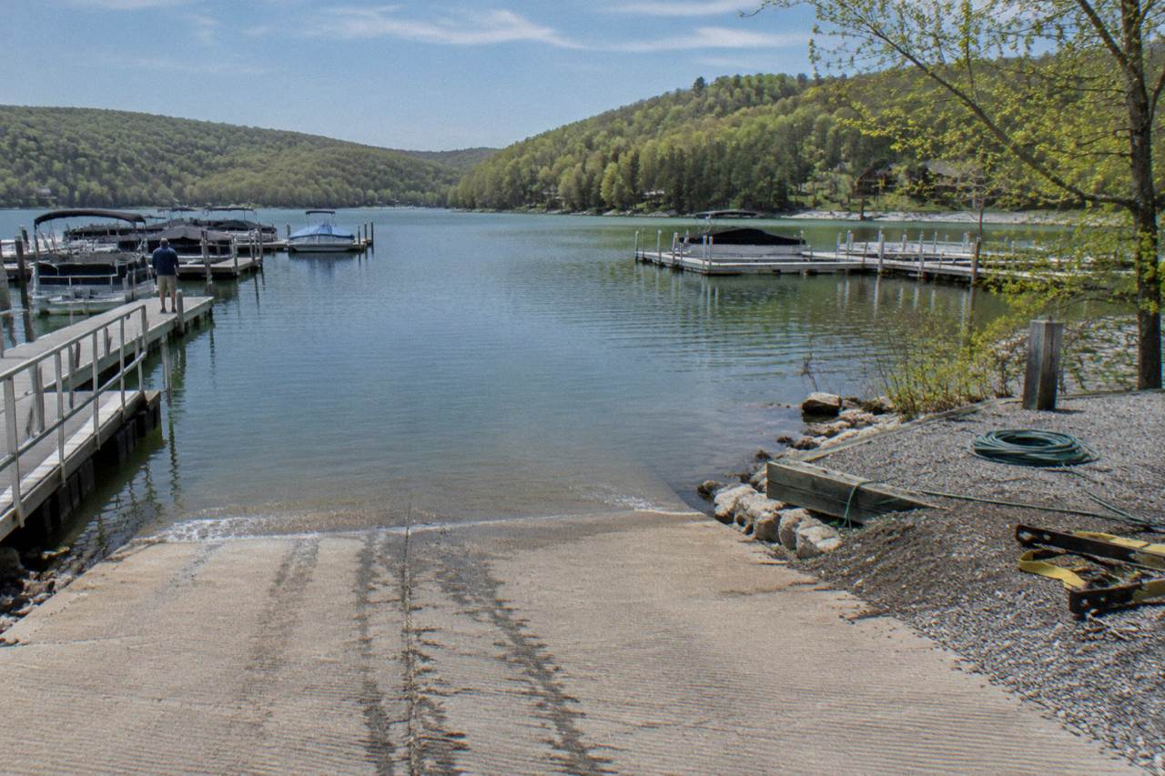 Boat ramp at a wooded lake shore with calm water and forested hills beyond