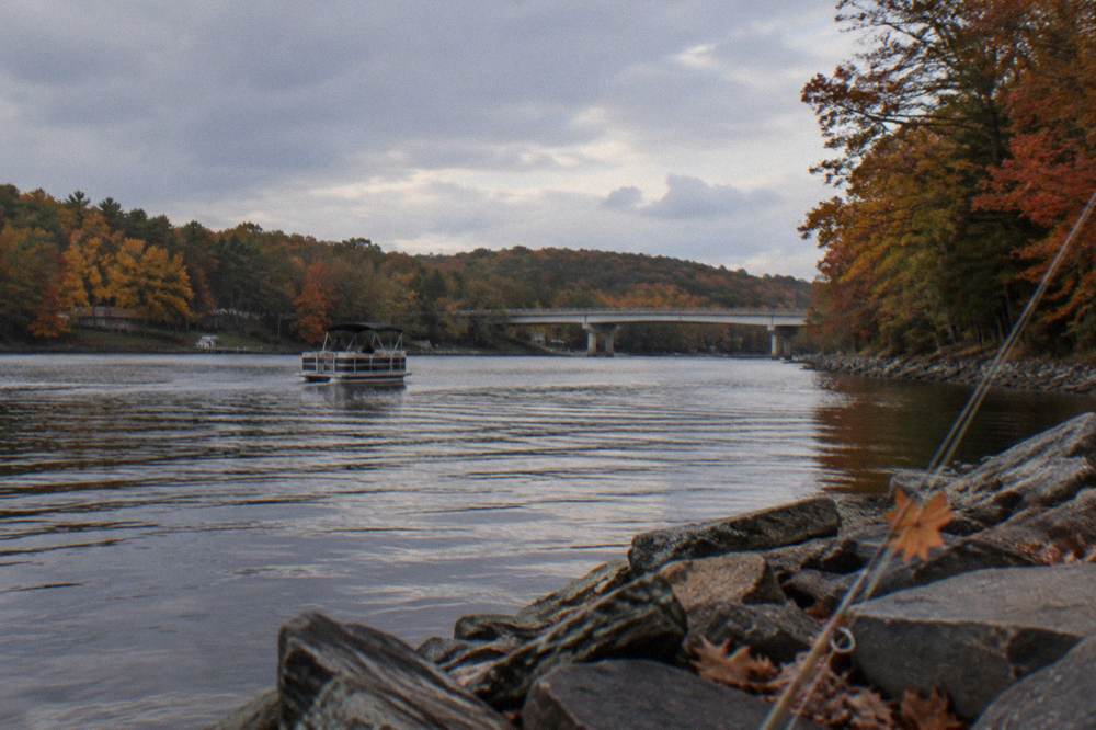 Boat drifting near a forested shoreline in bright fall color at Deep Creek Lake