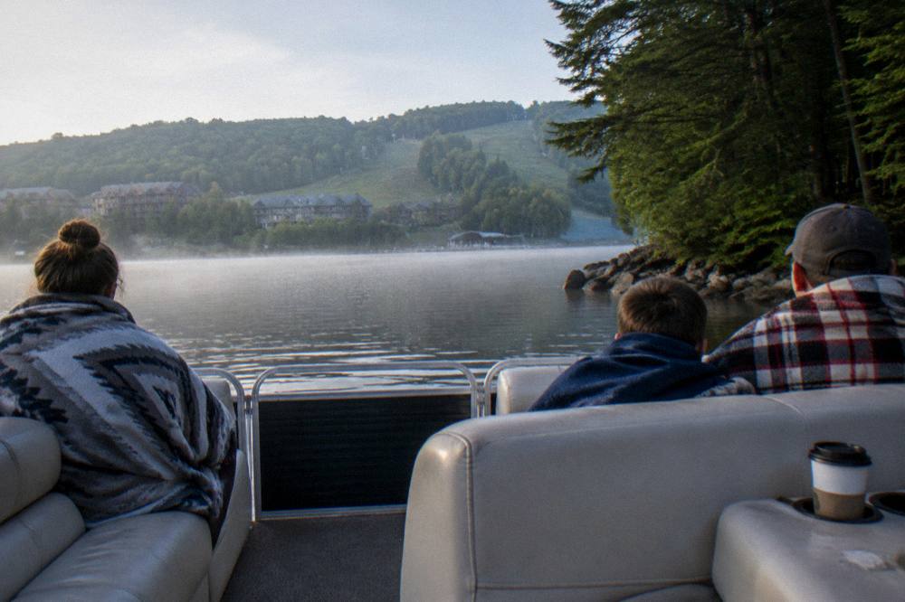Family relaxing on a pontoon boat near a quiet cove with morning light on the water