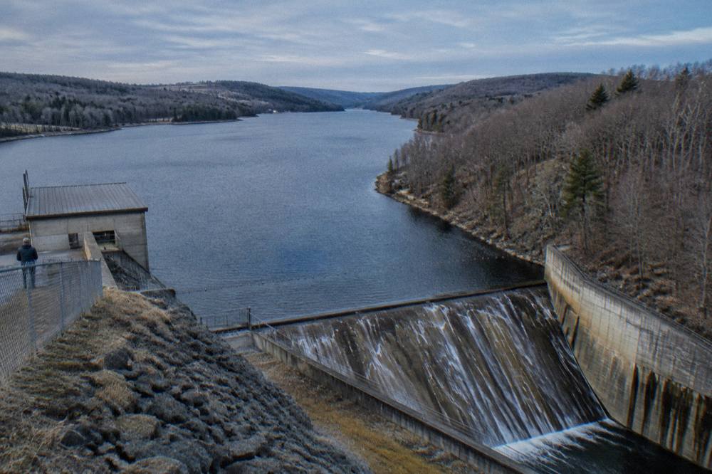 A wide view down a long narrow arm of Deep Creek Lake with wooded hills on both sides