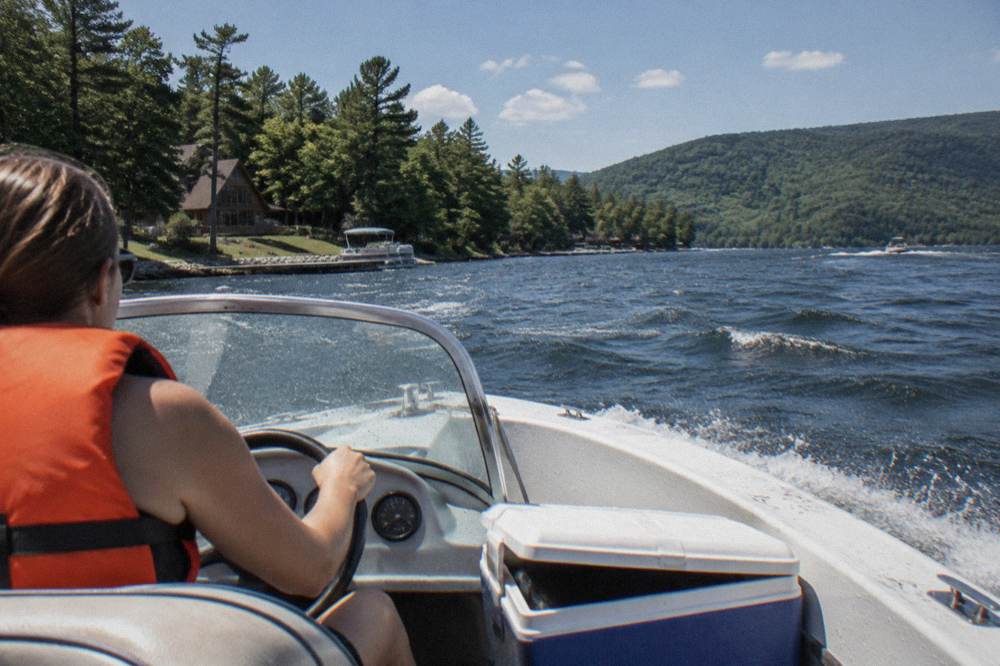 Boater at the helm of a small motorboat wearing a life jacket on open water