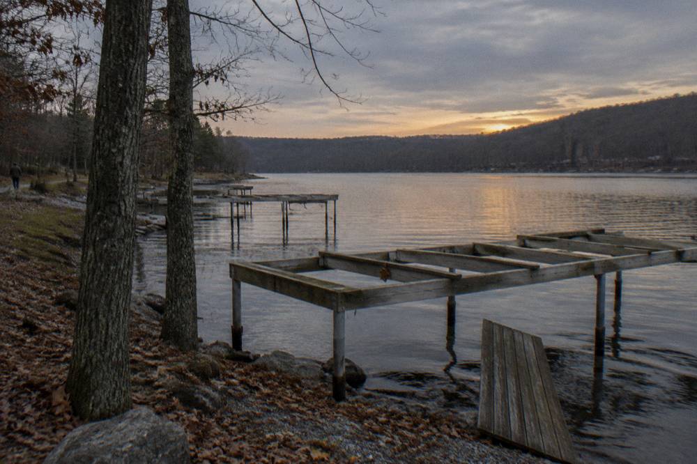Empty dock frames along a shoreline in late fall with bare trees and still water