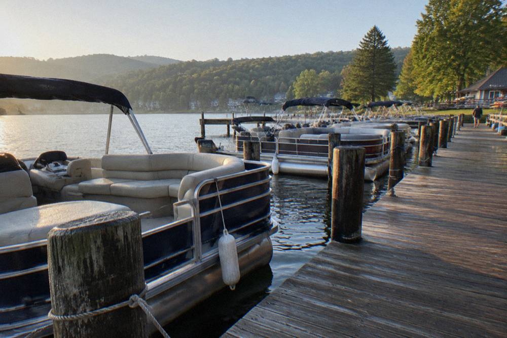 Rows of pontoon boats tied to rental docks on a summer morning