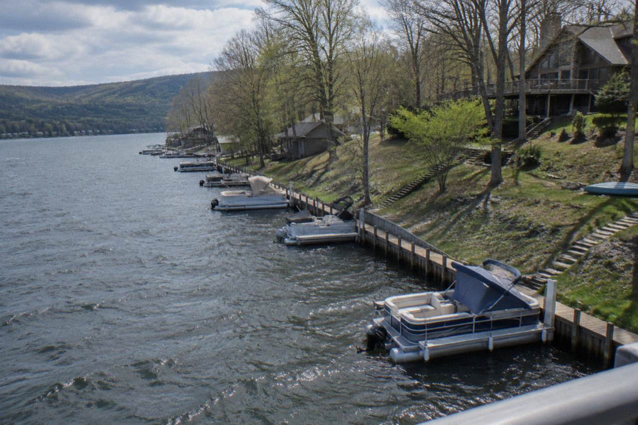 Pontoon boats moored on calm water along a wooded shoreline at Deep Creek Lake