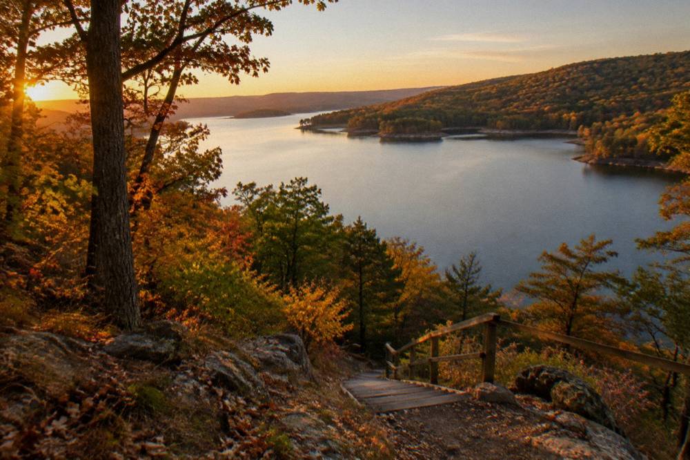 A wide lake at golden hour with autumn hillsides on both shores and no boats visible