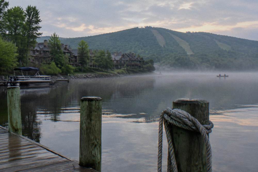 Wooden dock posts along a quiet lake cove with morning mist over the water