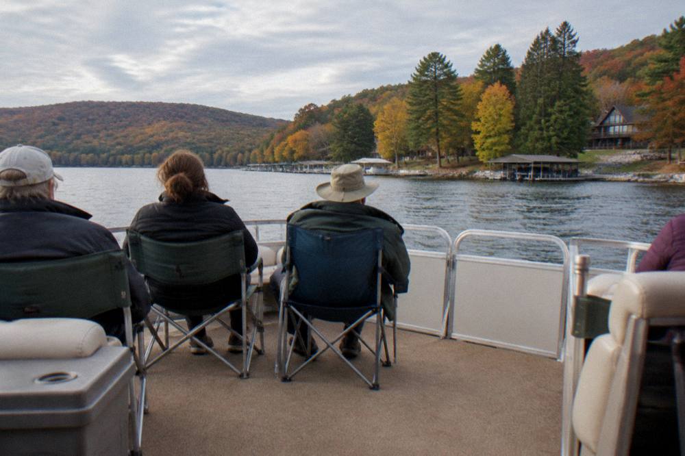 Group relaxing on the deck of a moving pontoon boat on a wide lake