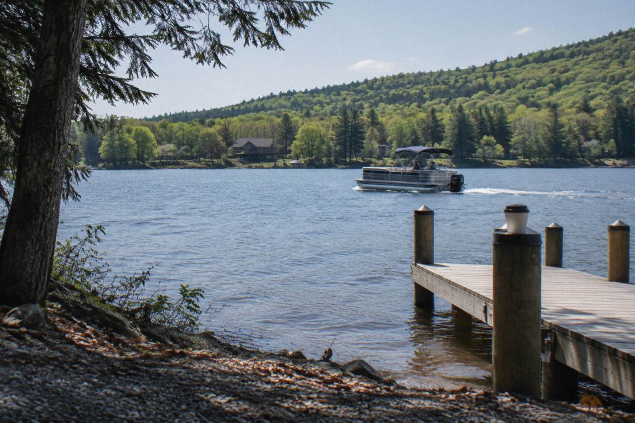 Pontoon boat cruising across open water at Deep Creek Lake with forested hills on the shoreline