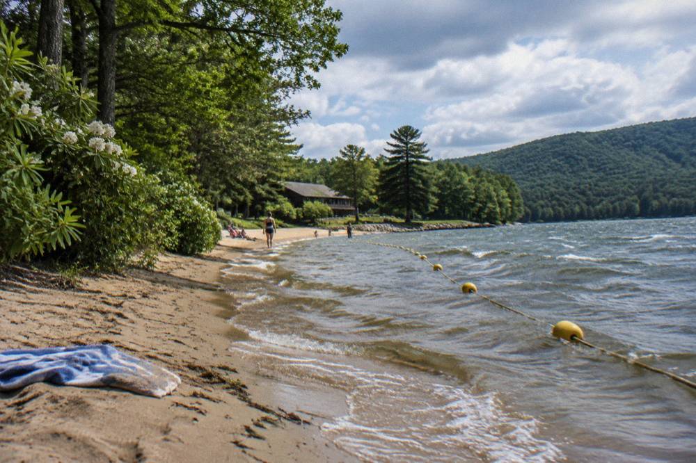 Sandy beach at Deep Creek Lake State Park with trees along the shore