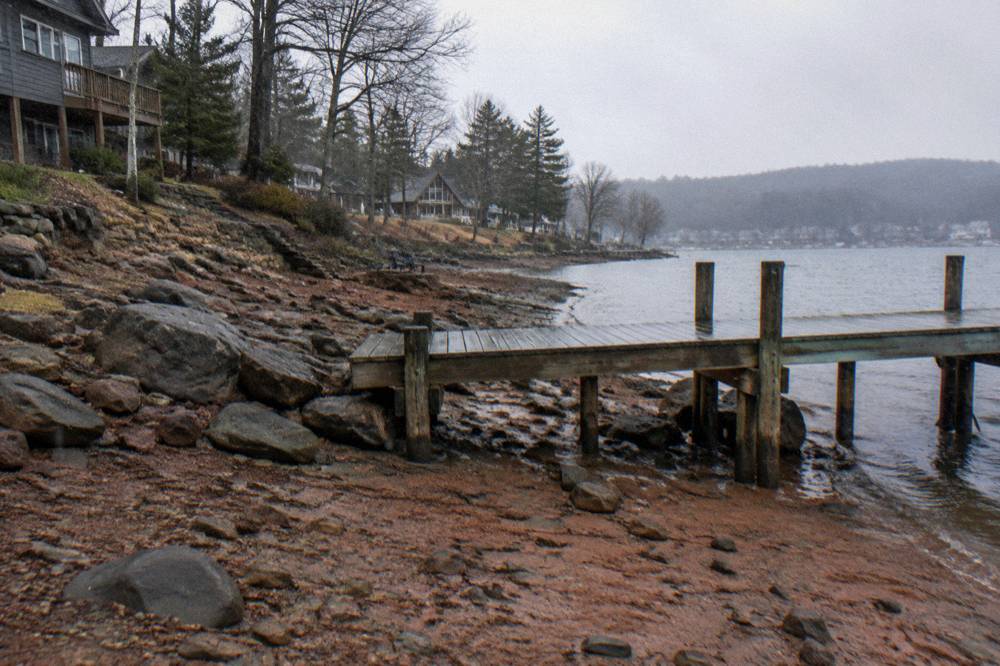 A wooden dock standing above a lowered lake shoreline with exposed rocks