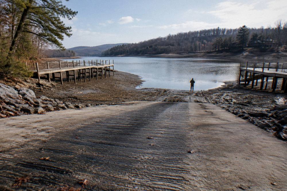 A concrete boat ramp reaching into lake water between wooden dock sections