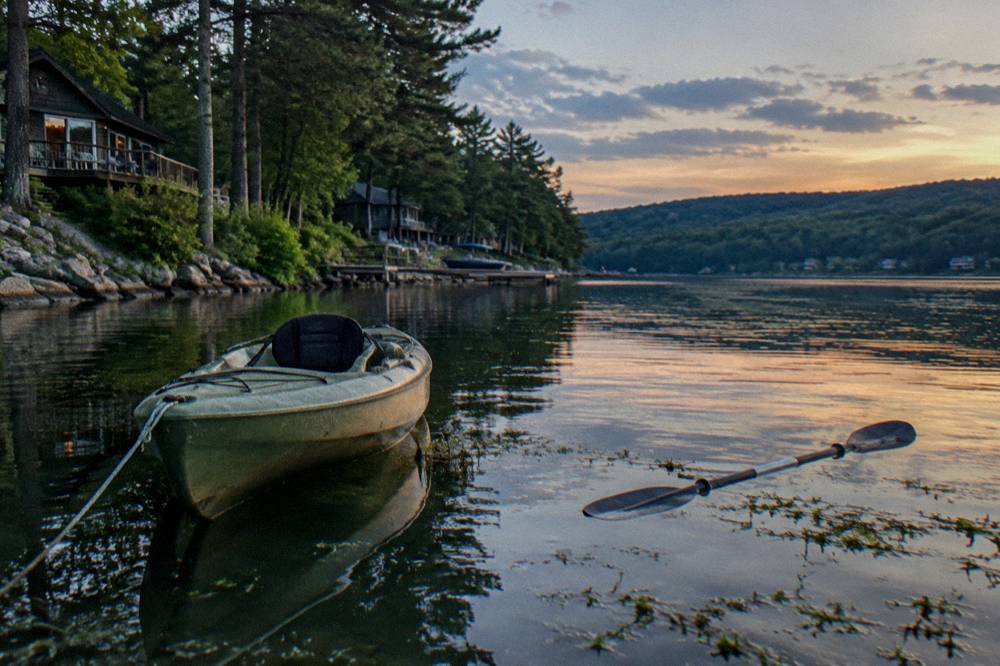 Kayak floating on flat water near a forested lake shore