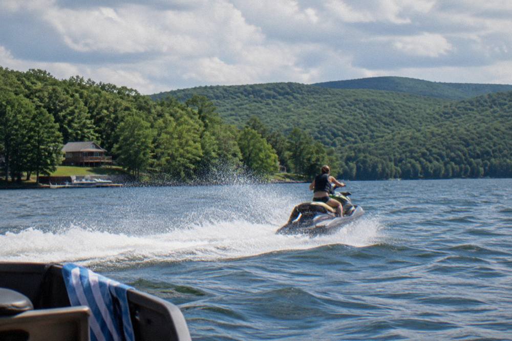 A personal watercraft cutting across open water with tree-covered ridges in the background