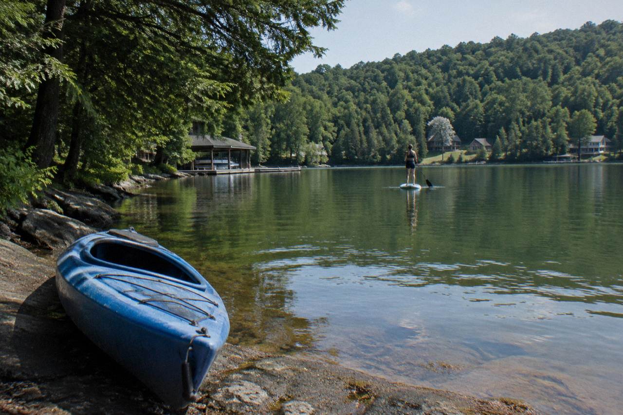 Calm green water of a lake cove with forested hills in the background