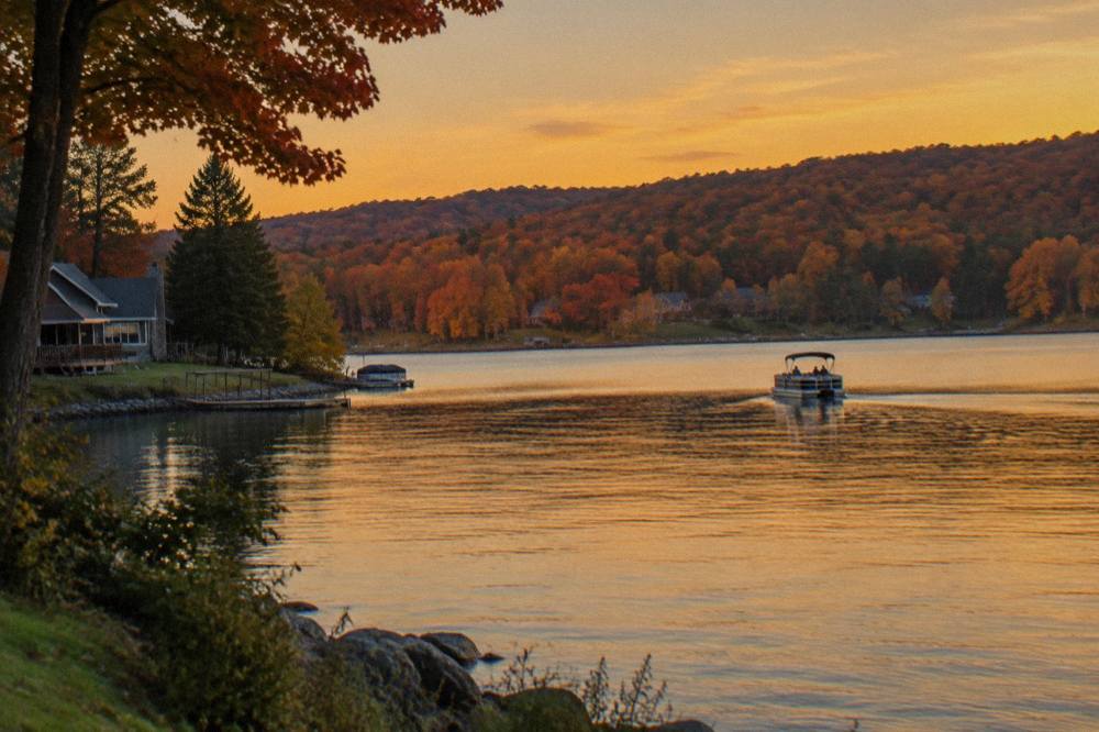 A pontoon boat drifting on still water under a golden evening sky