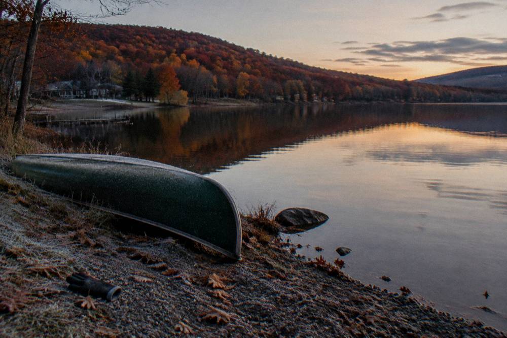 Fall hillsides in red and orange reflected in still lake water at dusk