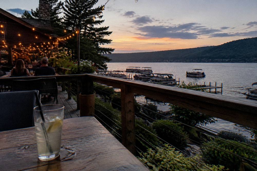 A lakeside restaurant deck with string lights glowing at dusk