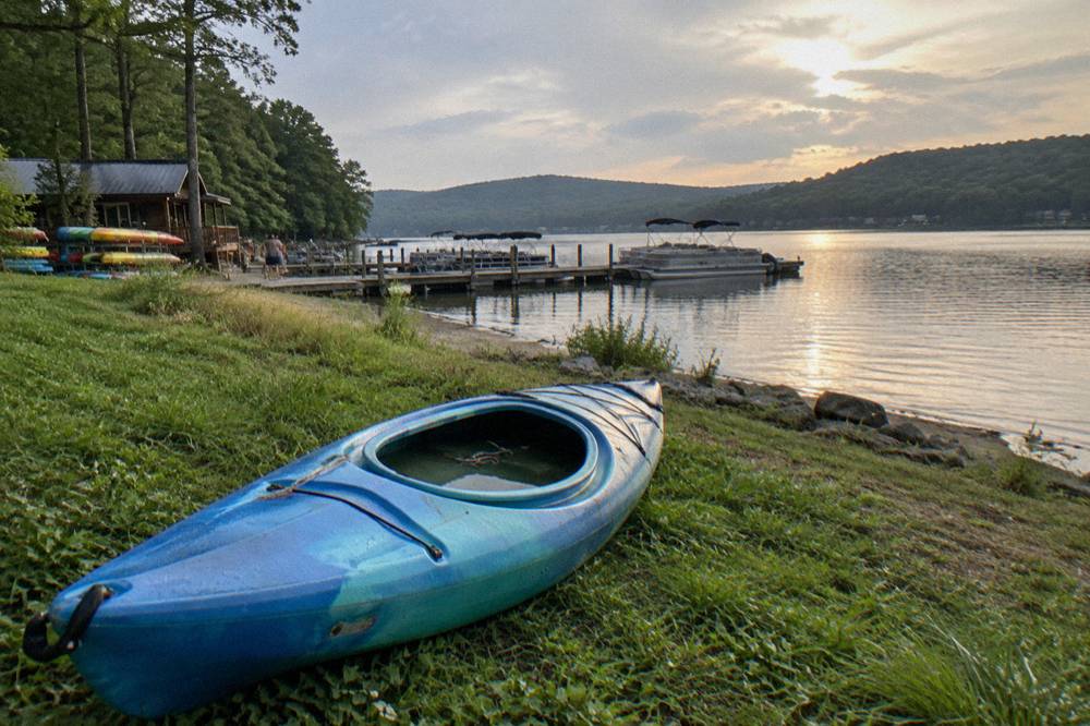 Calm cove water with a kayak pulled onto a grassy bank at Deep Creek Lake