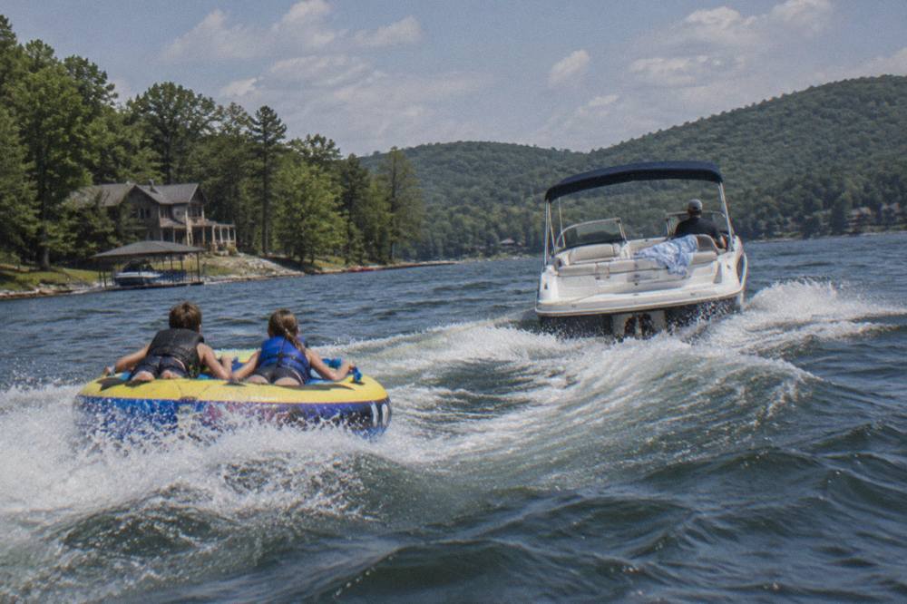 Speed boat pulling an inflatable tube across a wide mountain lake