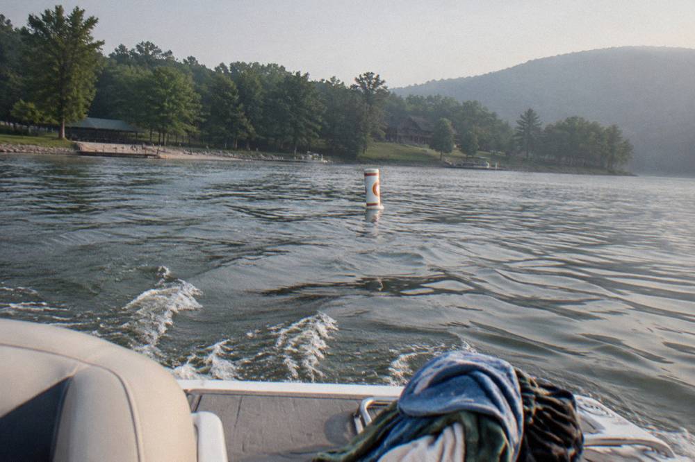 White regulatory buoy with an orange circle floating near a wooded lakeshore