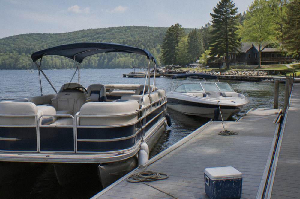 Pontoon boat and speed boat tied to a dock at a lake rental marina