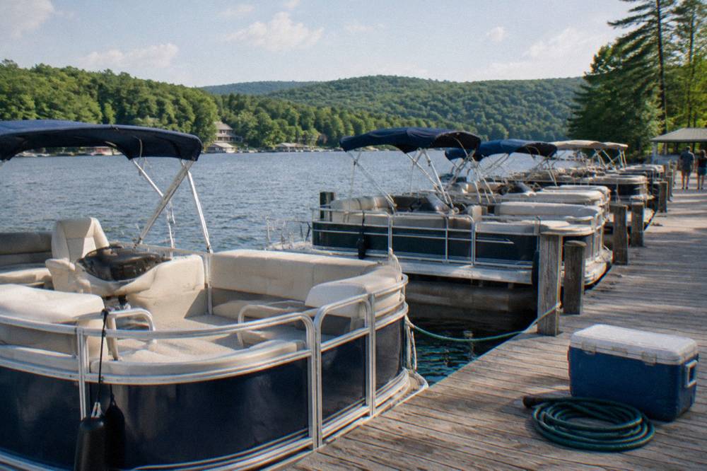 Rental pontoons tied along a dock with forested hills rising behind the lake