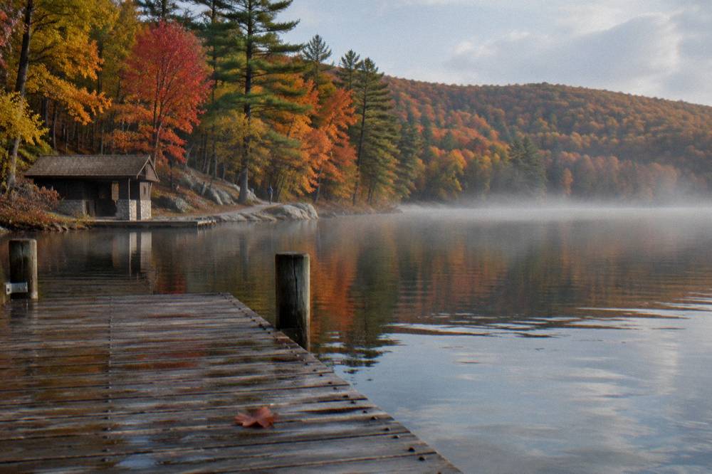 Lake shoreline with autumn color reflecting on calm water near a wooden dock